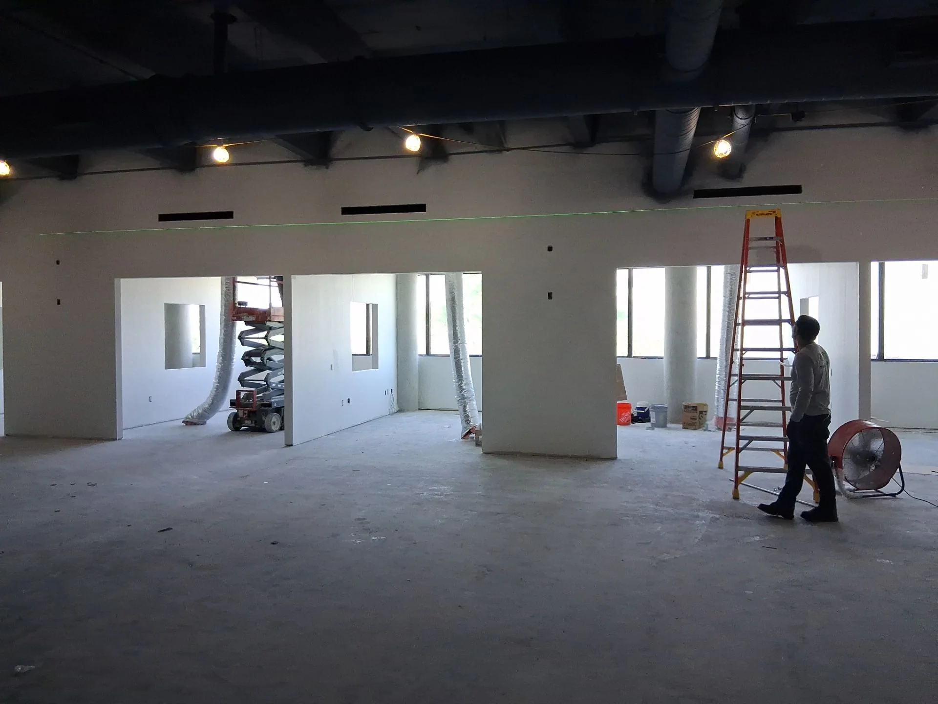 Interior construction progress with ladder and workers