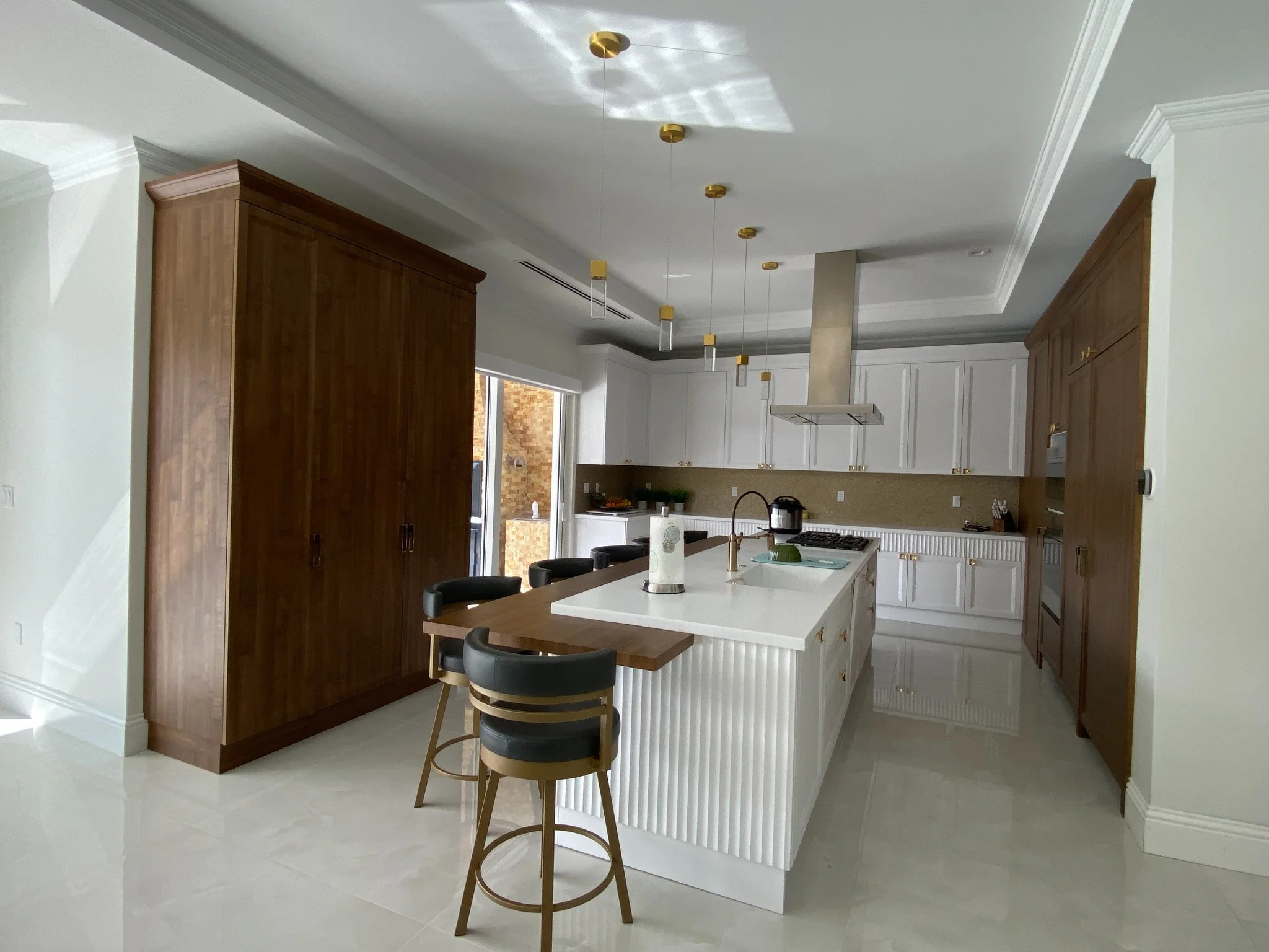 Custom kitchen with walnut cabinetry, waterfall island, open-plan layout, and abundant natural light.