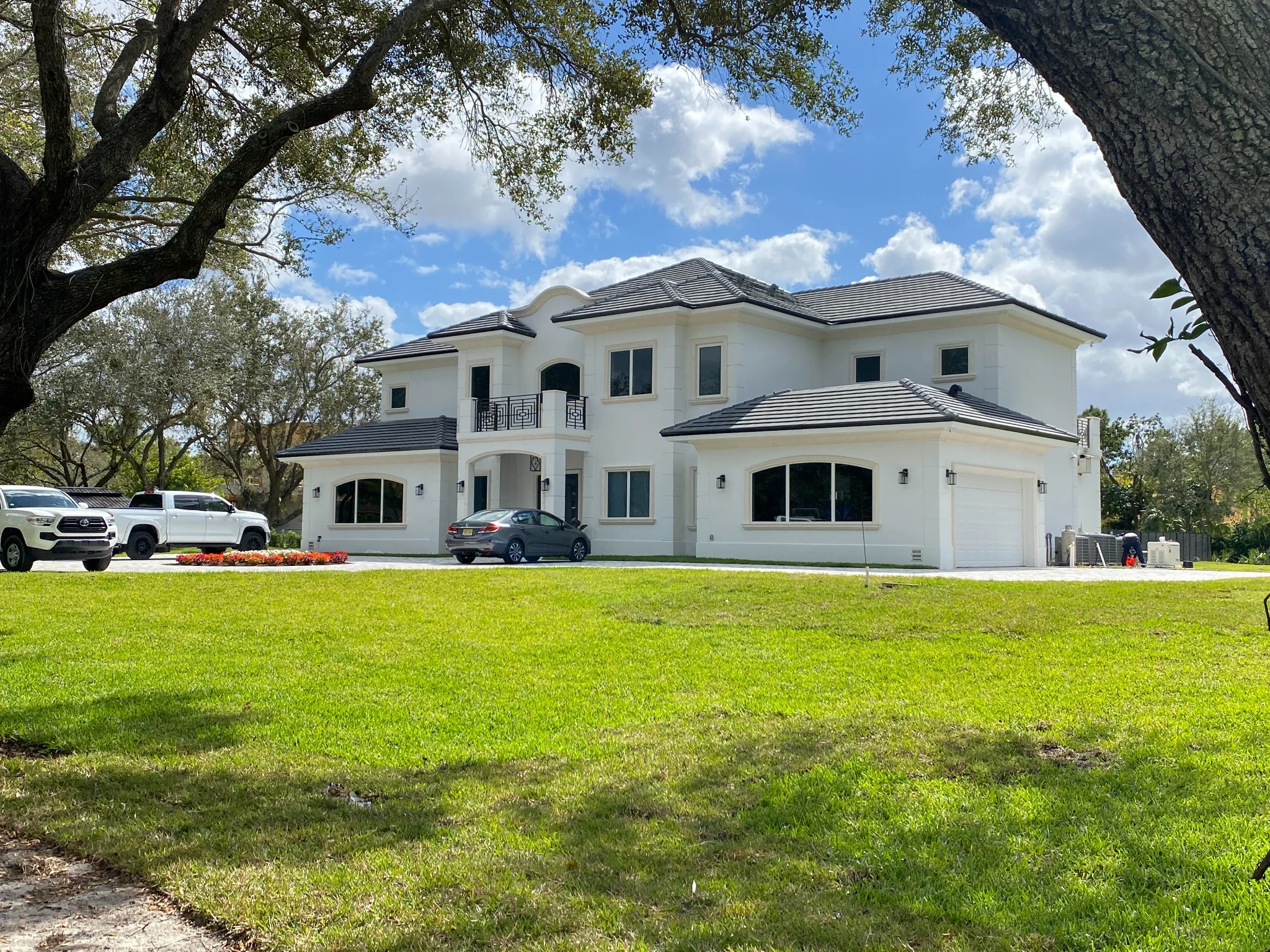 Completed luxury estate front elevation framed by mature trees and landscape